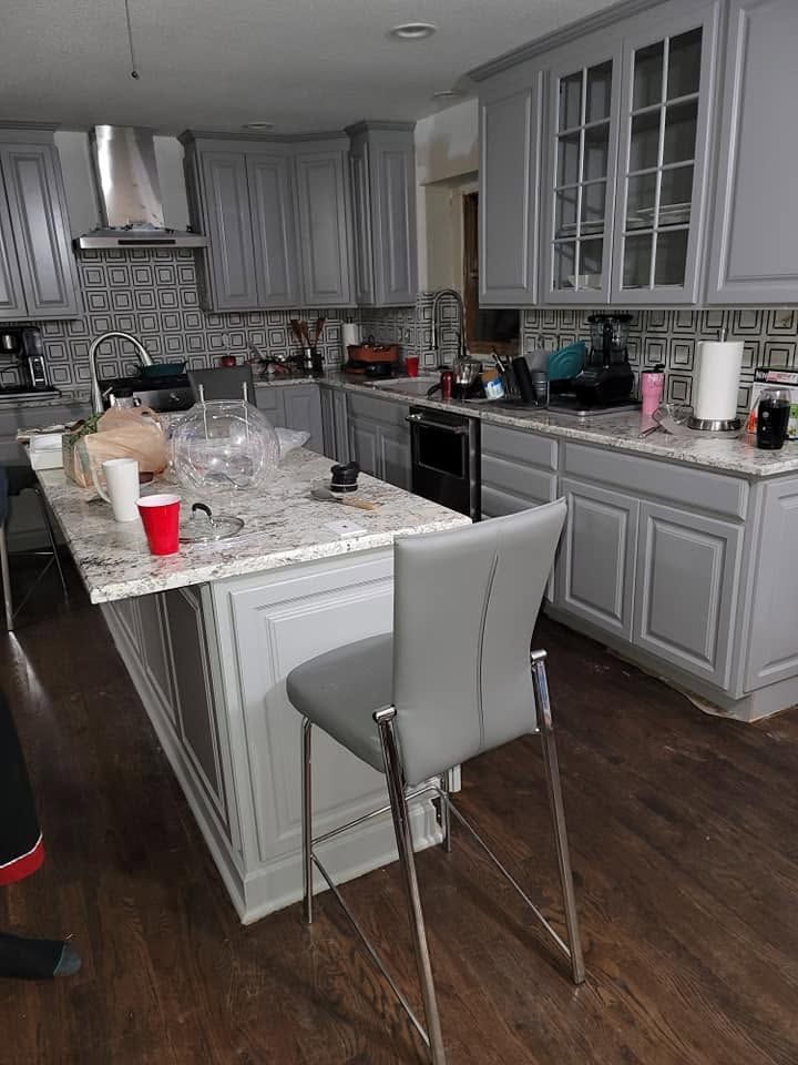 A kitchen with gray cabinets , granite counter tops , and a large island.
