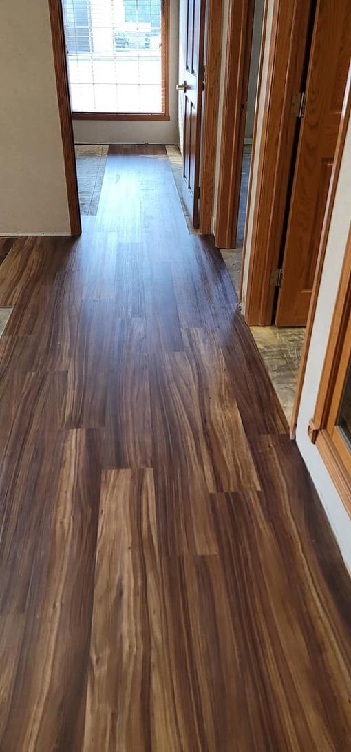 A hallway with a wooden floor and a window.