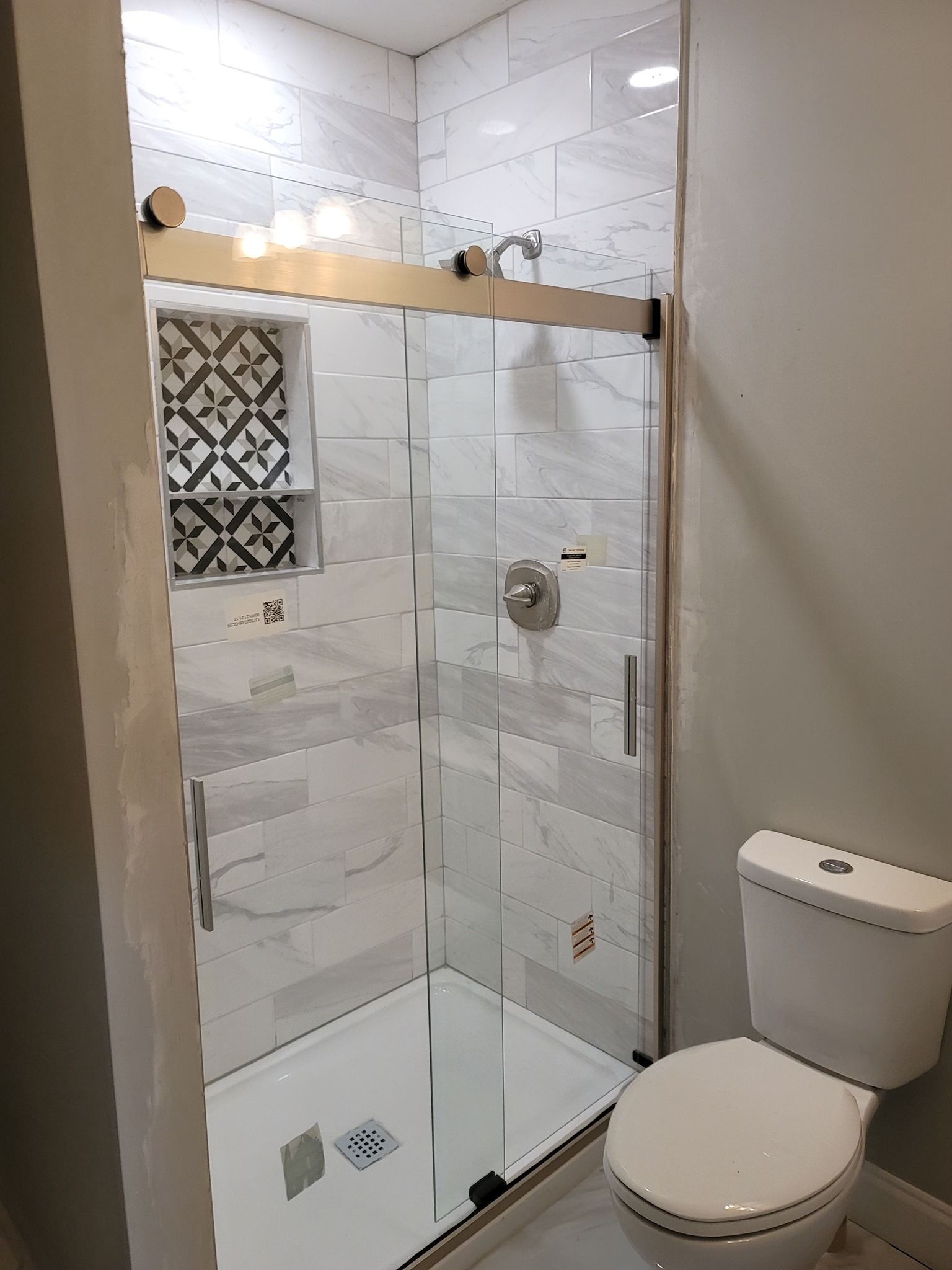 A bathroom with a toilet , shower and sliding glass door.