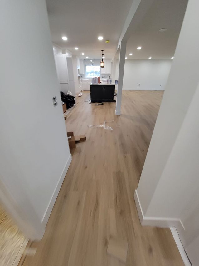 A hallway leading to a kitchen with hardwood floors and white walls.