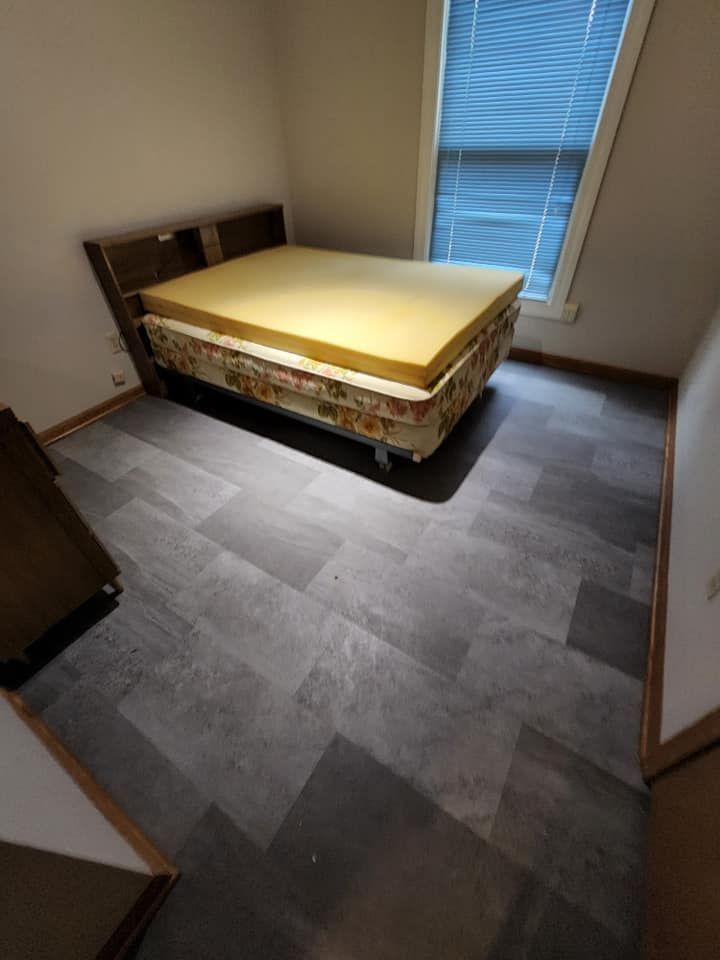 A bedroom with a bed and a window with blinds