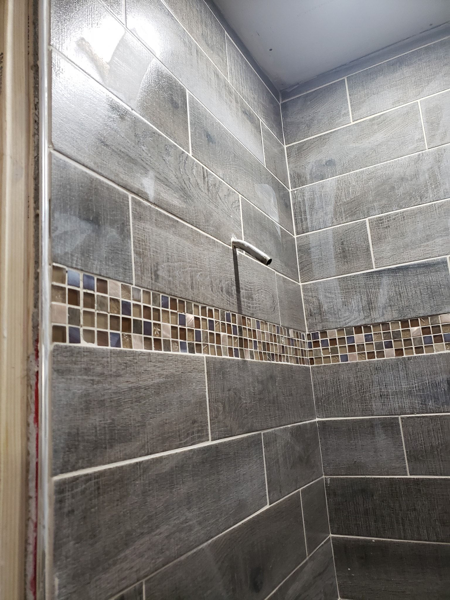 A bathroom with gray tiles and a mosaic border.