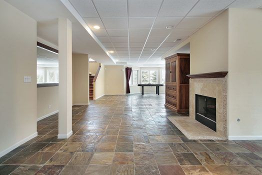 An empty basement with tile floors and a fireplace