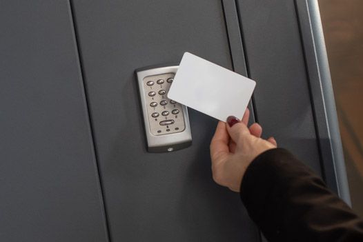 Person using a key card to unlock a grey safe.