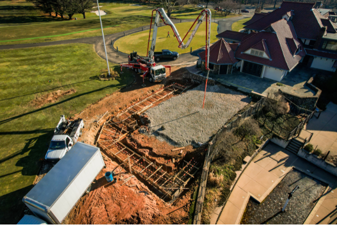 An aerial view of a construction site with a large house in the background