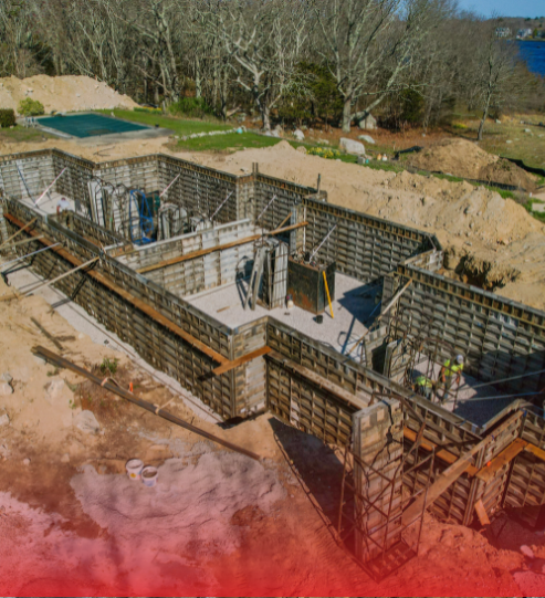 An aerial view of a house under construction with a pool in the background.