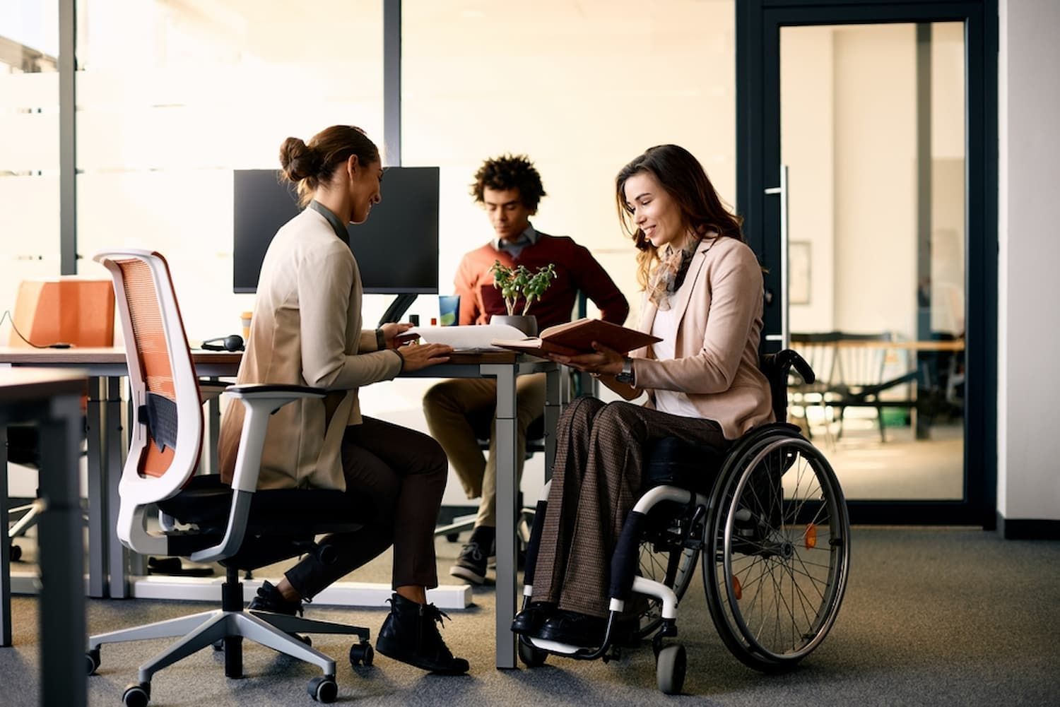 A Woman in A Wheelchair Is Sitting at A Table with Two Other People — Wonder Care Australia Pty Ltd in Kearneys Spring, QLD