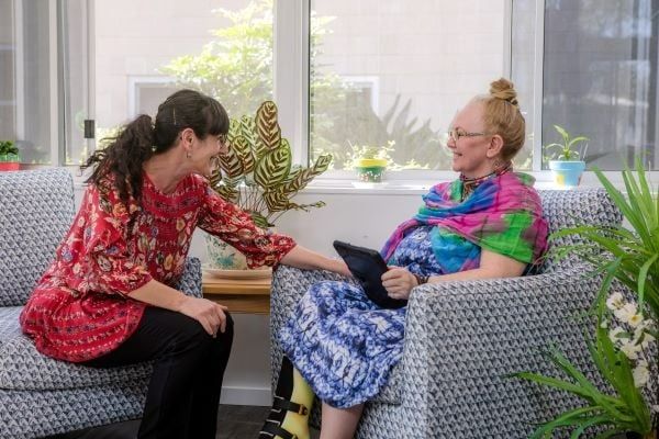 Two Women Are Sitting on A Couch Talking to Each Other — Wonder Care Australia Pty Ltd in Kearneys Spring, QLD