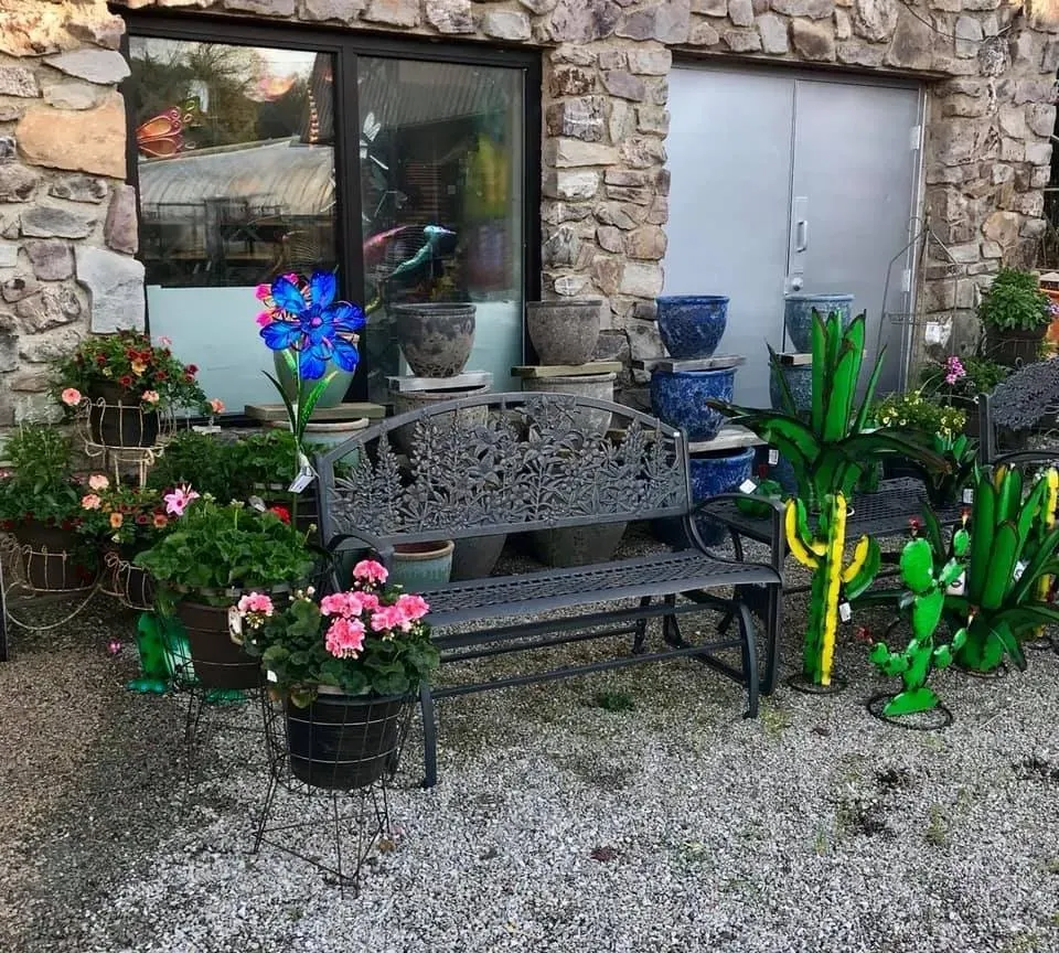 A bench surrounded by potted plants in front of a stone building