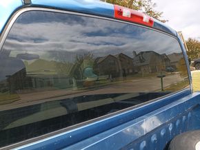 A view of the rear window of a blue truck.