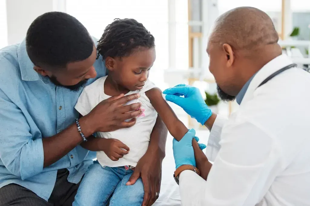 Doctor giving a child a vaccine while a man holds the child.