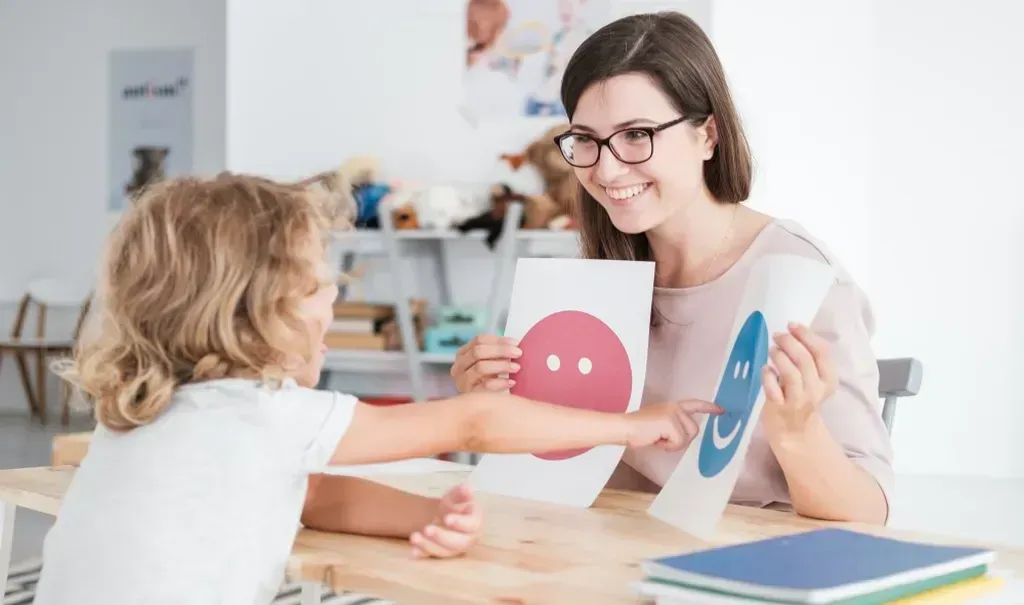 Woman giving a child a picture of a smiley face.