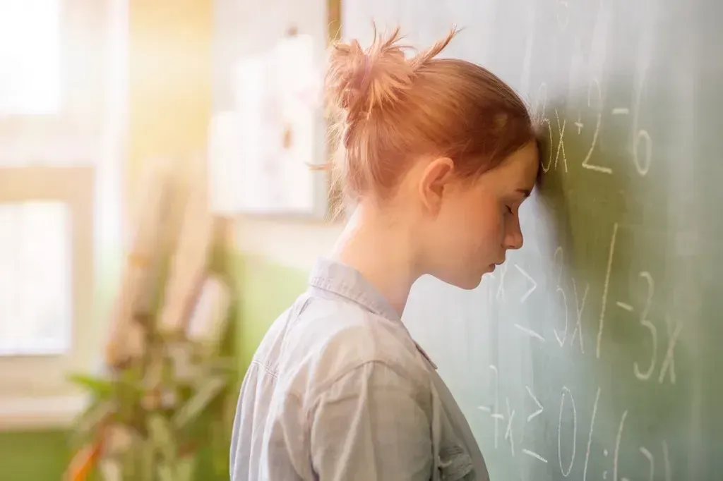 Woman with her head against chalkboard.