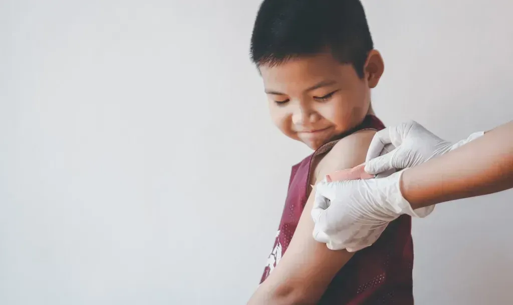 Young boy getting a band-aid on his arm.