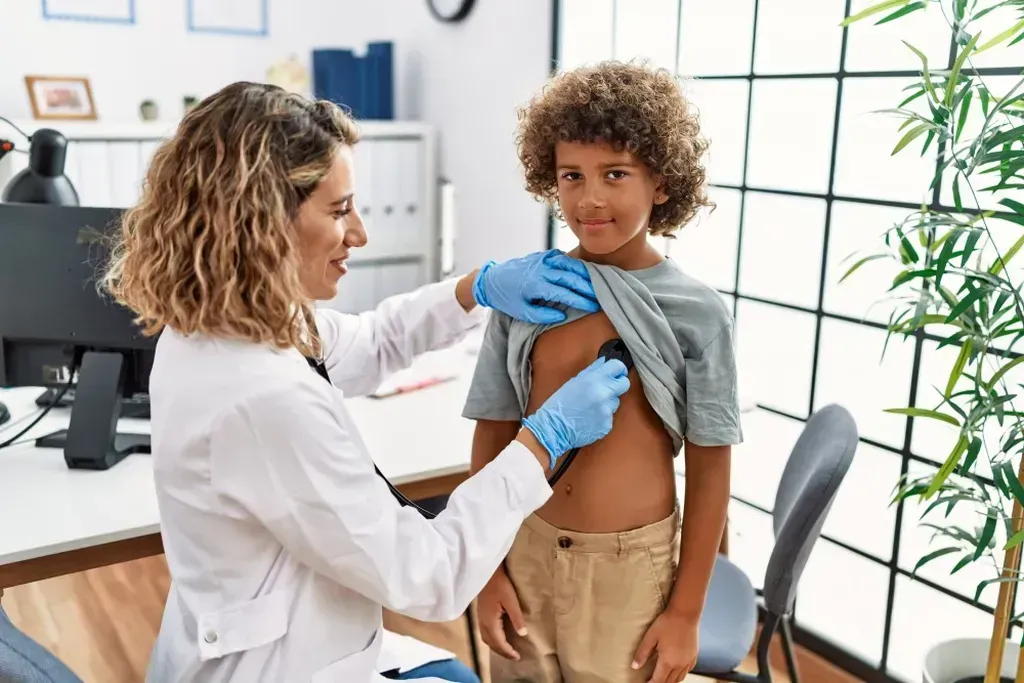 Doctor examining a young boy with a stethoscope.
