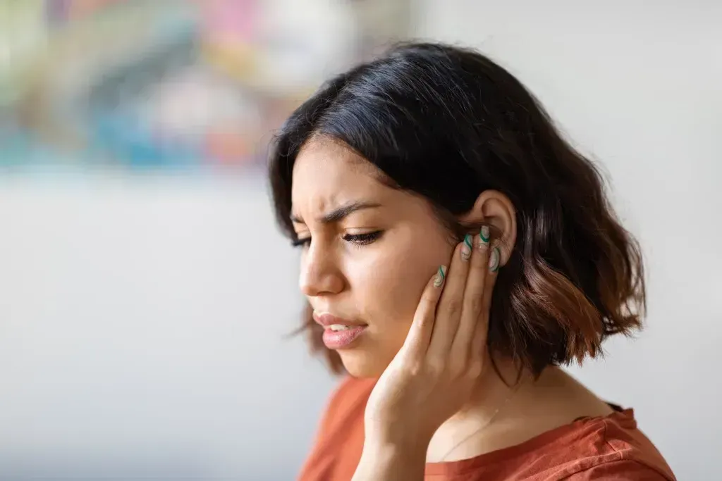 Woman is holding her ear because she has an ear infection.