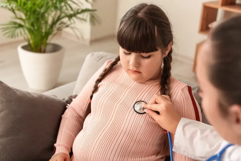 Doctor listening to a little girl 's heart with a stethoscope.