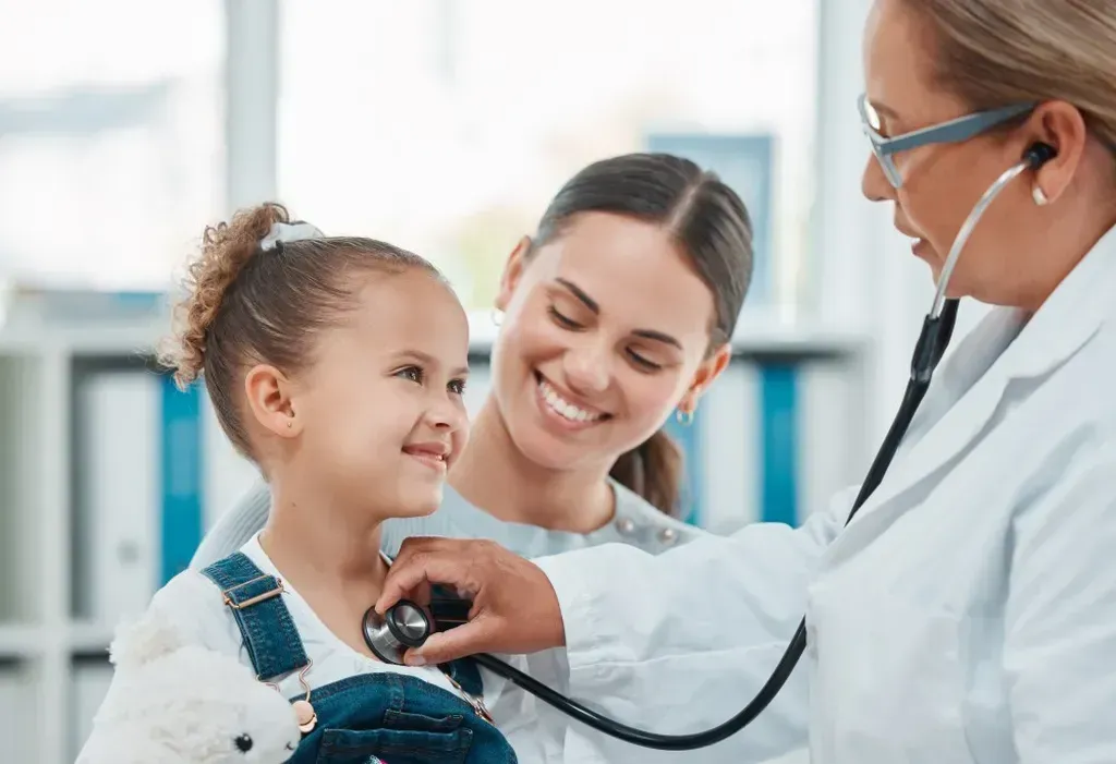 Doctor listening to a little girl 's heart with a stethoscope.