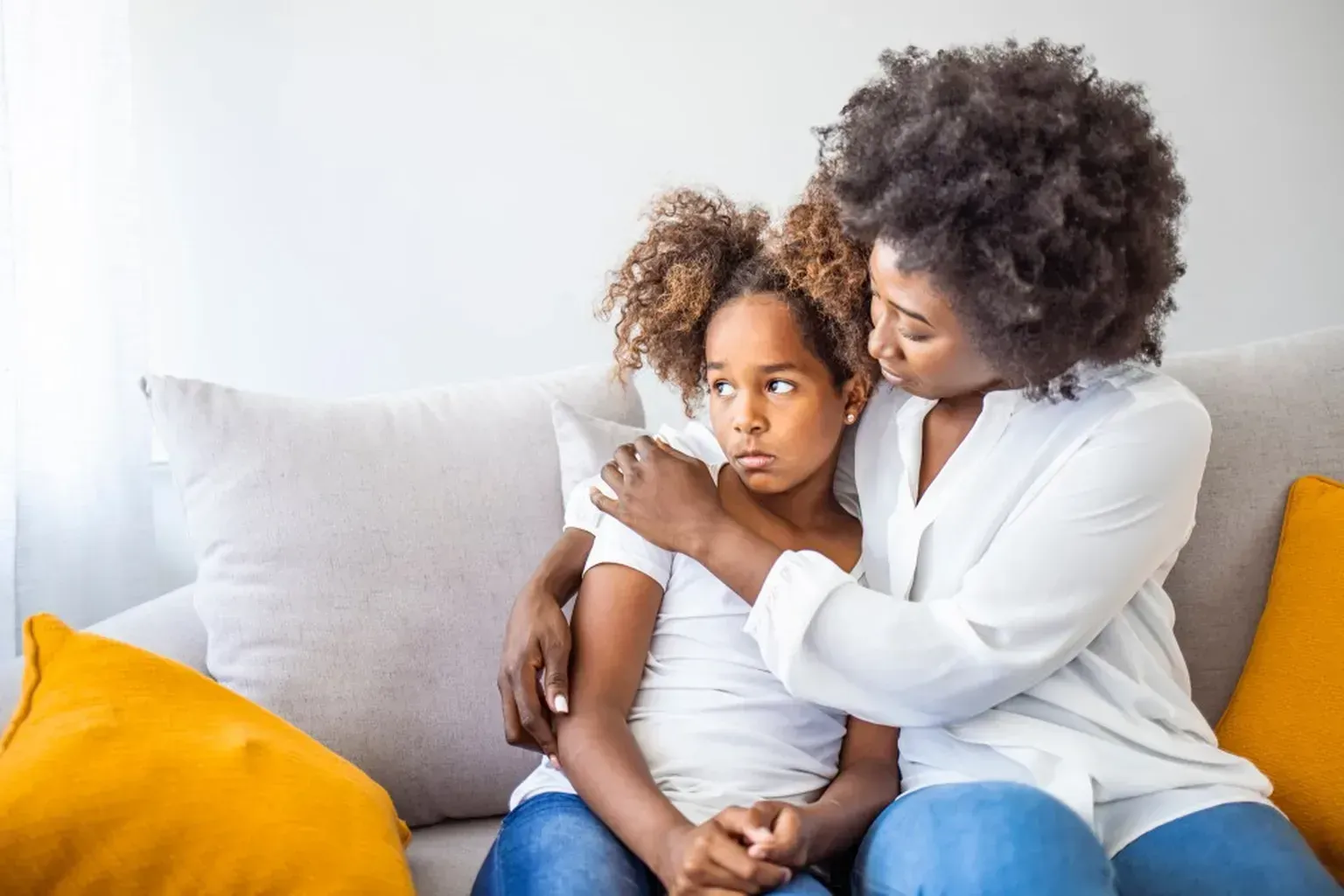A woman is sitting on a couch with a little girl.