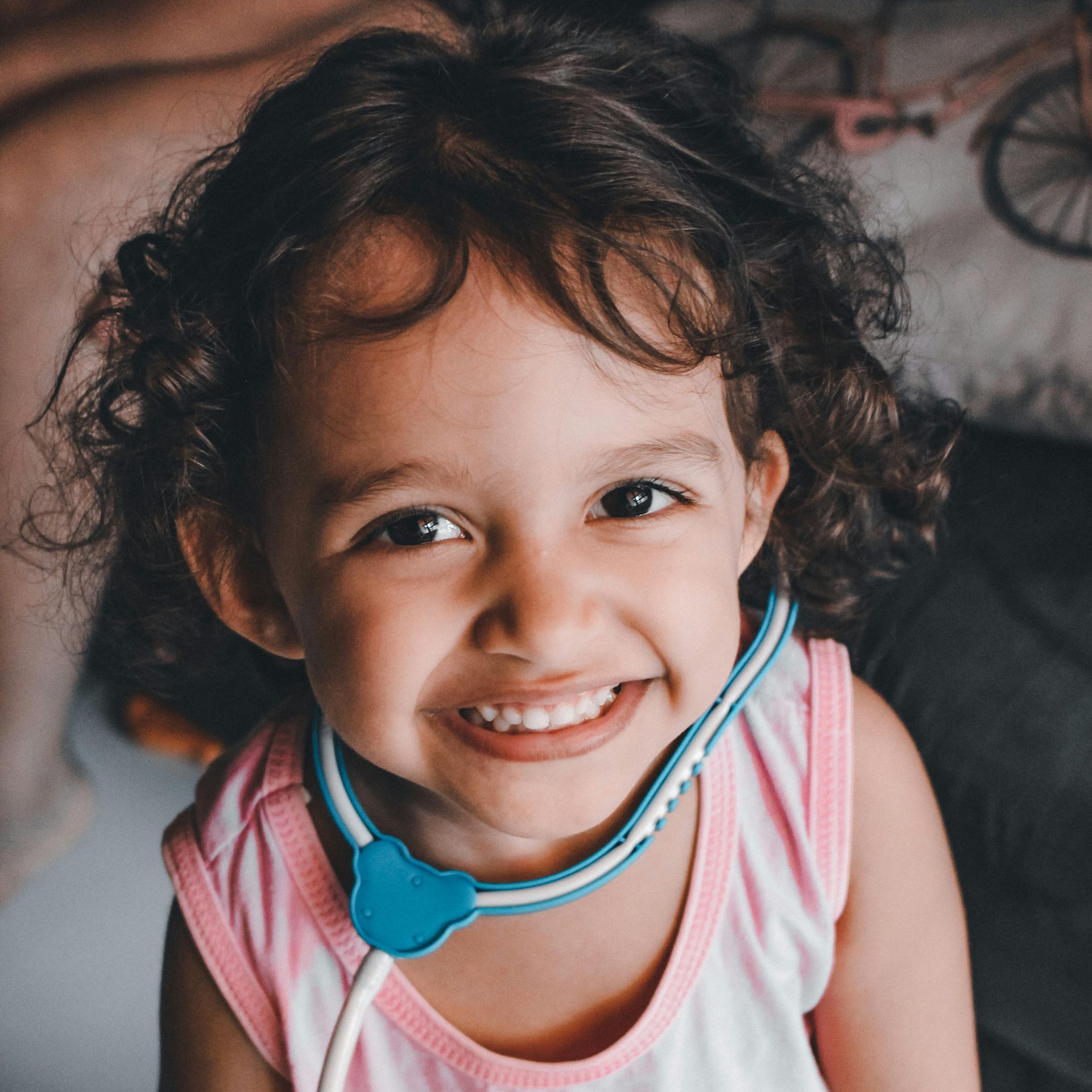 A little girl is wearing a stethoscope around her neck and smiling