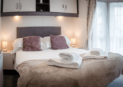 Modern kitchen with white and dark cabinets, countertop fruit bowl, stove, and window with blinds.