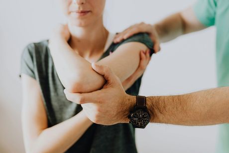 Hands supporting a person’s bent arm during a medical or physical therapy exam