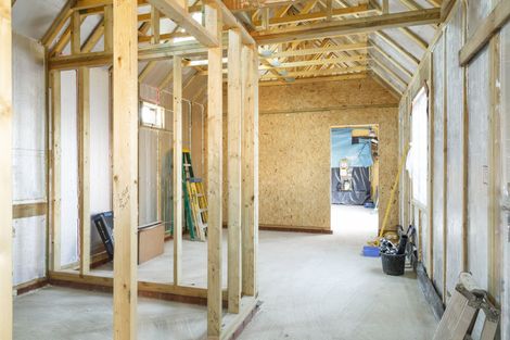 Intérieur d'une maison en construction avec charpente en bois apparente et murs non finis.