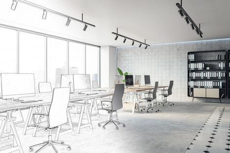 Bureau moderne à aire ouverte avec bureaux, chaises, éclairage sur rail et étagère le long d'une paroi vitrée.