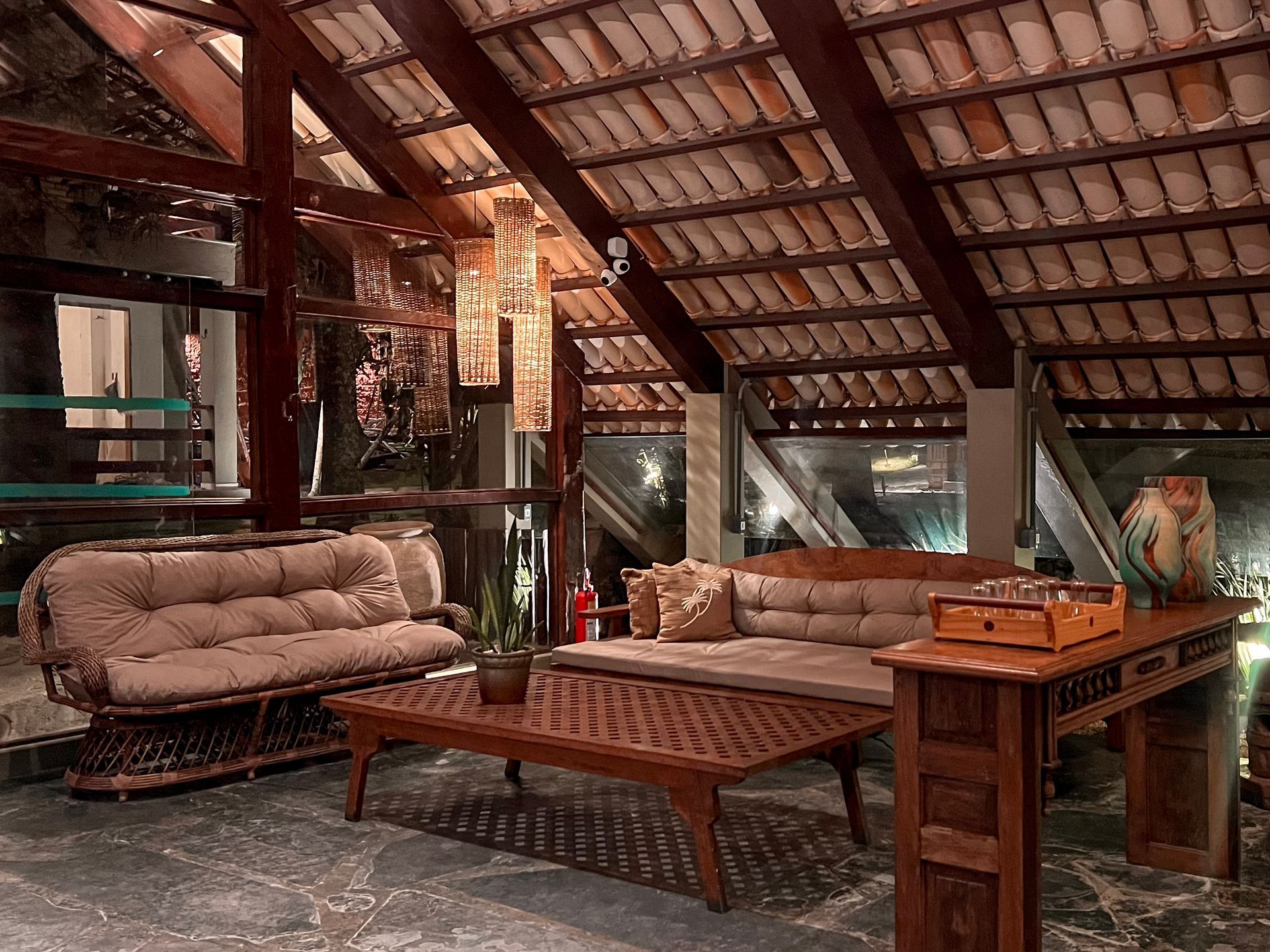 Pátio interno com móveis de madeira e teto com vigas aparentes.