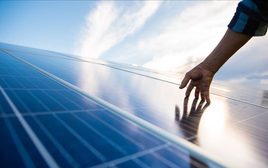 Una persona tocca un pannello solare con la mano.