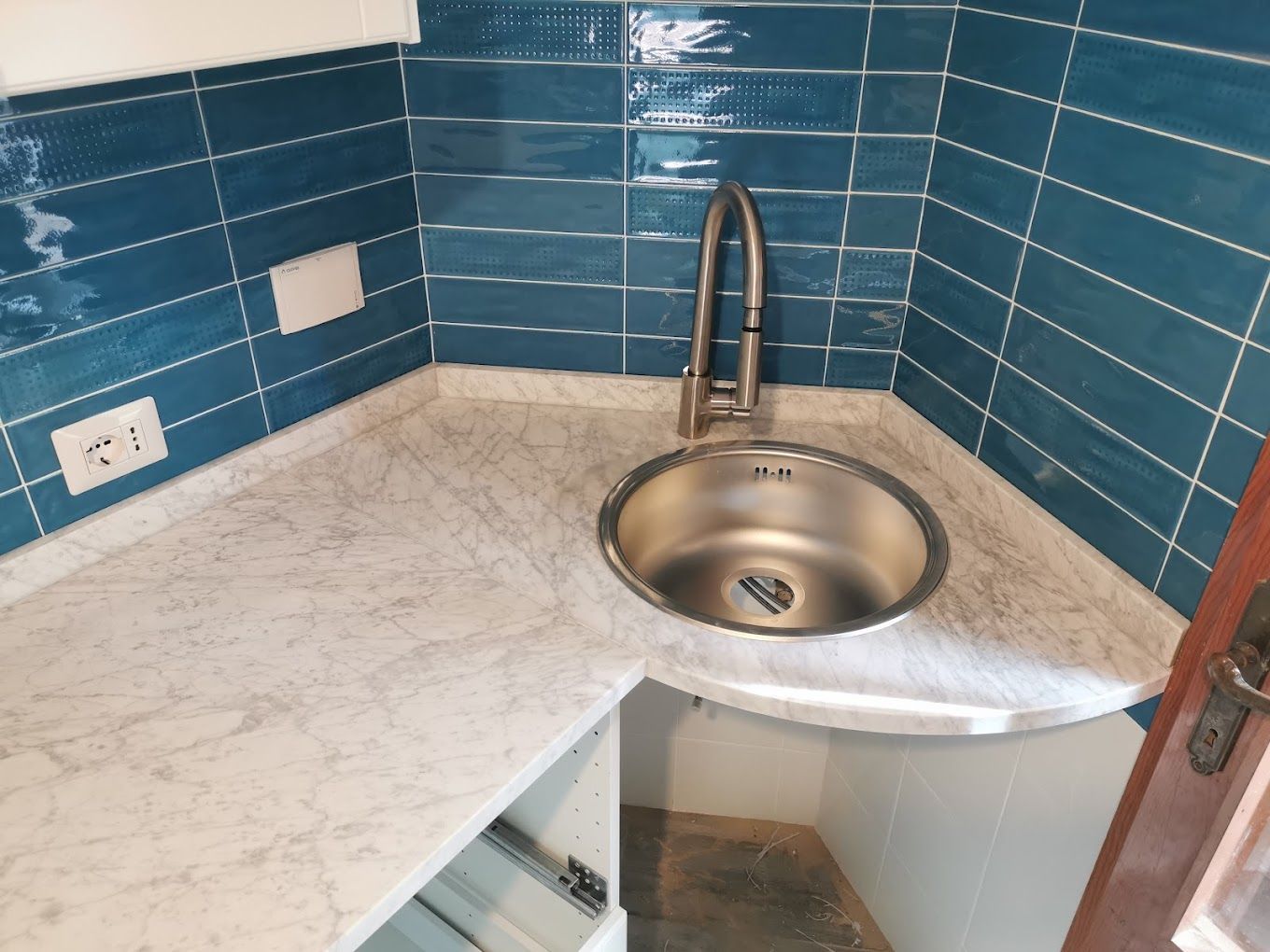 Un bagno con lavello e piastrelle blu alle pareti