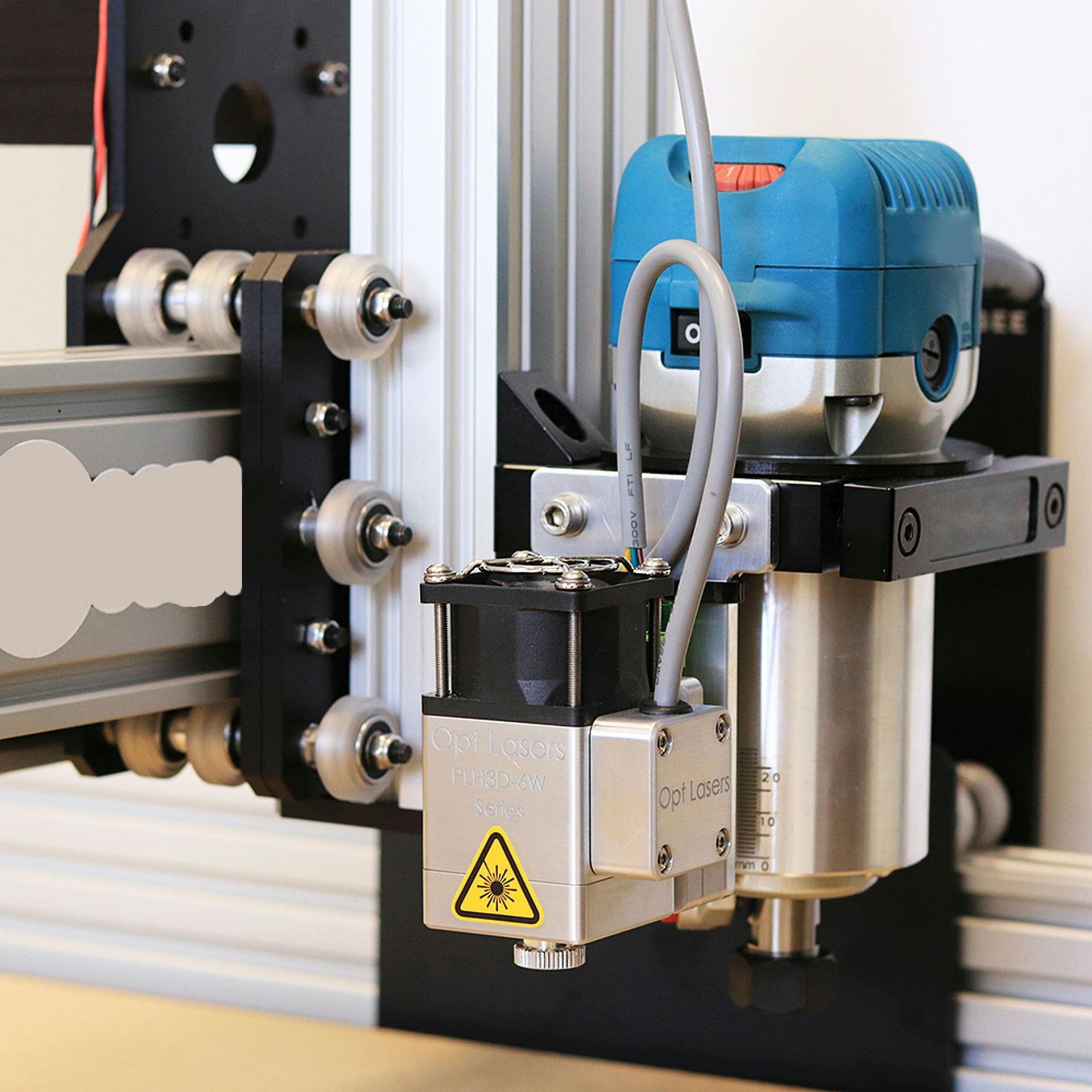 CNC machine with a laser and router attachment, mounted on a metal frame.