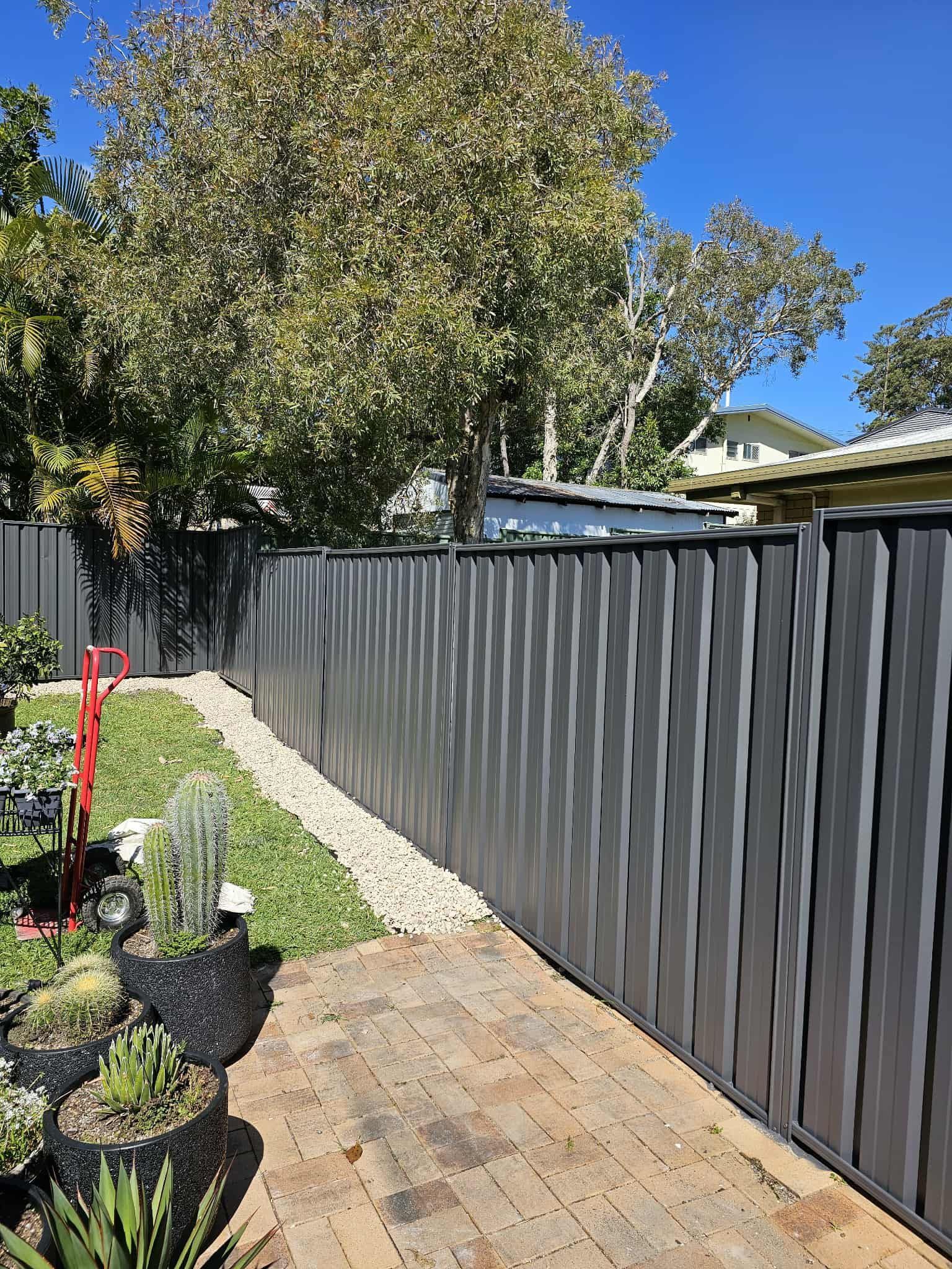 Gray Corrugated Metal Fence in a Backyard, Beside a Stone — MVP Painting Professionals in Sunshine Coast, QLD