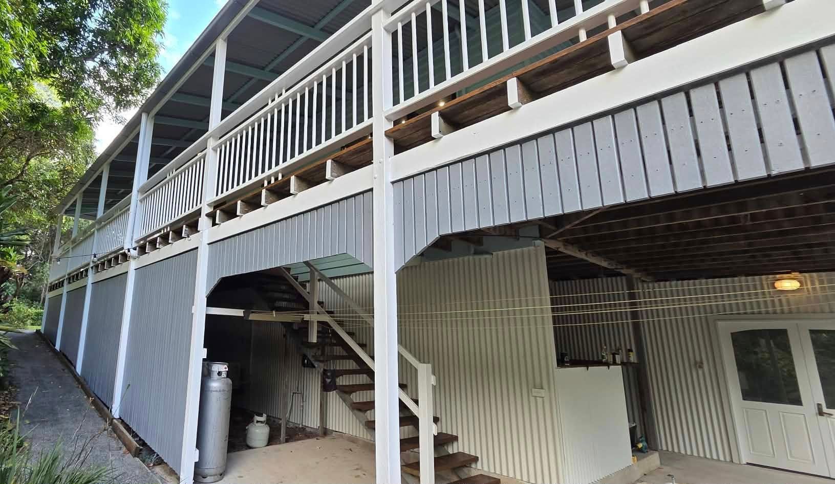 Two-story house with grey siding and wooden stairs leading to a porch — MVP Painting Professionals in Sunshine Coast, QLD