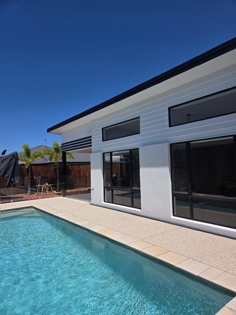 Poolside view of a modern white house with large windows, black trim — MVP Painting Professionals in Caloundra, QLD