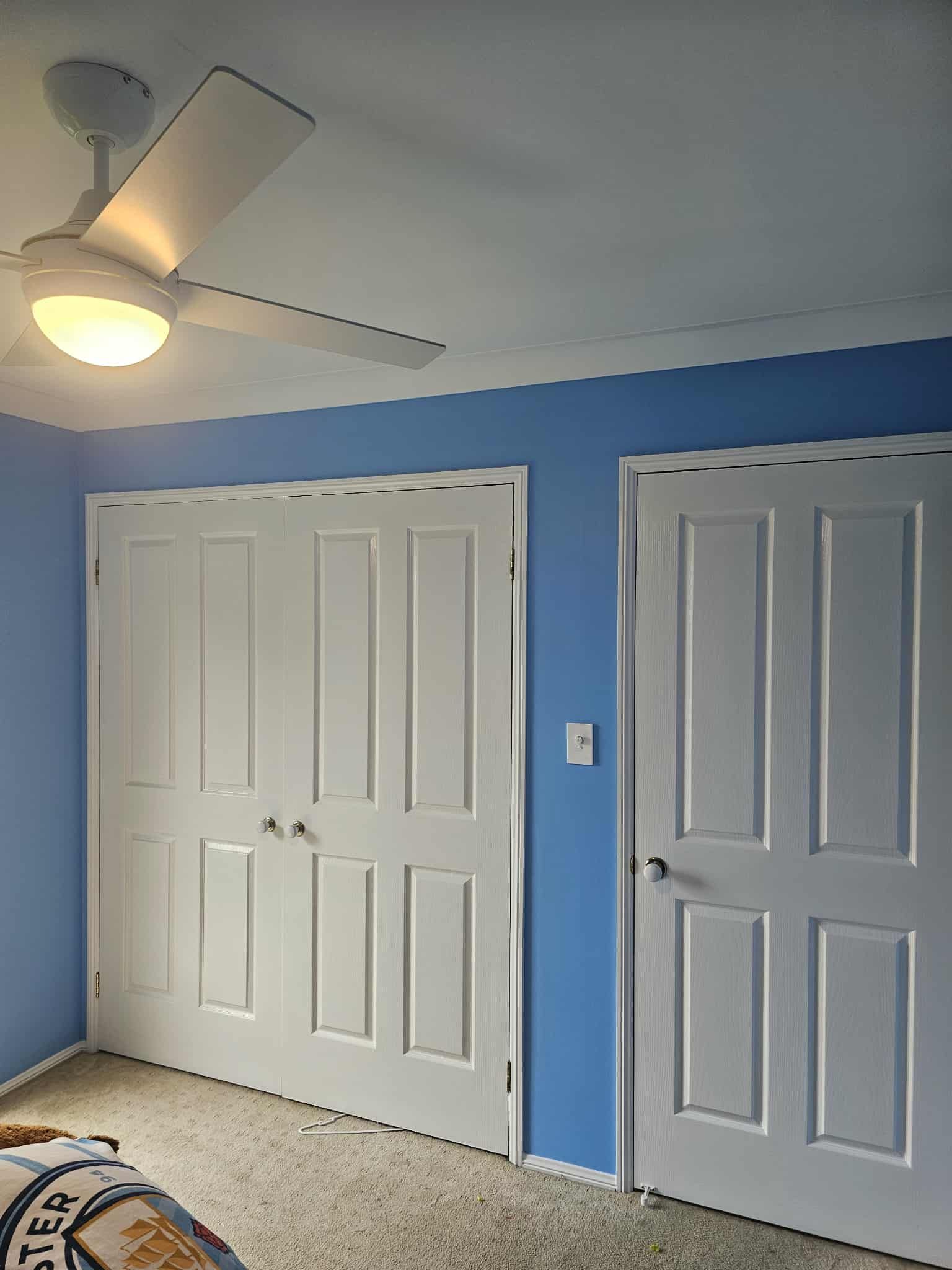 White closet doors and a door on a blue wall with a ceiling fan — MVP Painting Professionals in Kawana, QLD
