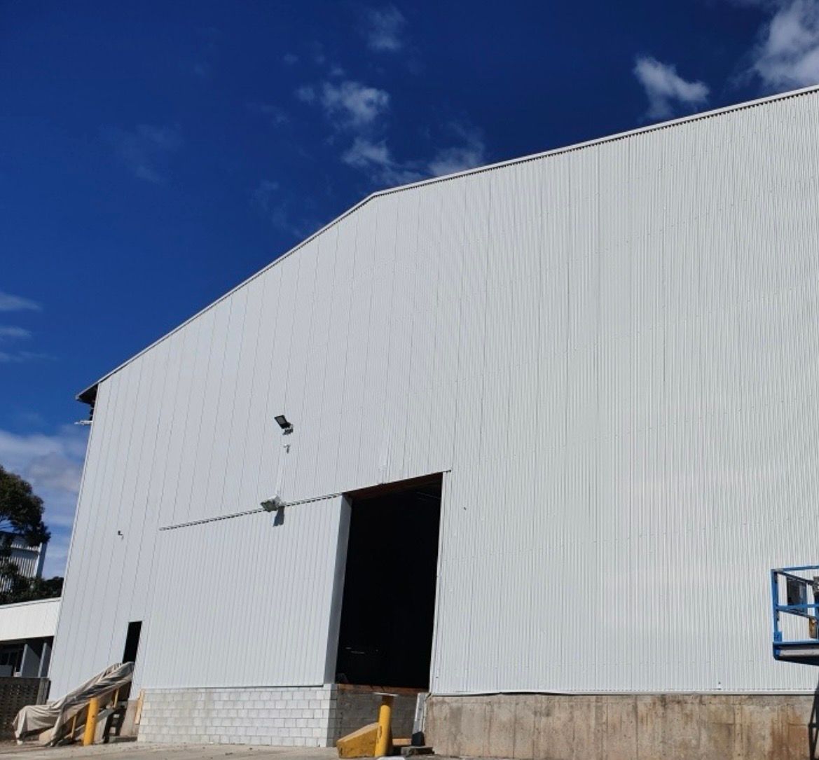 White industrial building with loading dock, open door, and blue sky — MVP Painting Professionals in Maroochydore, QLD