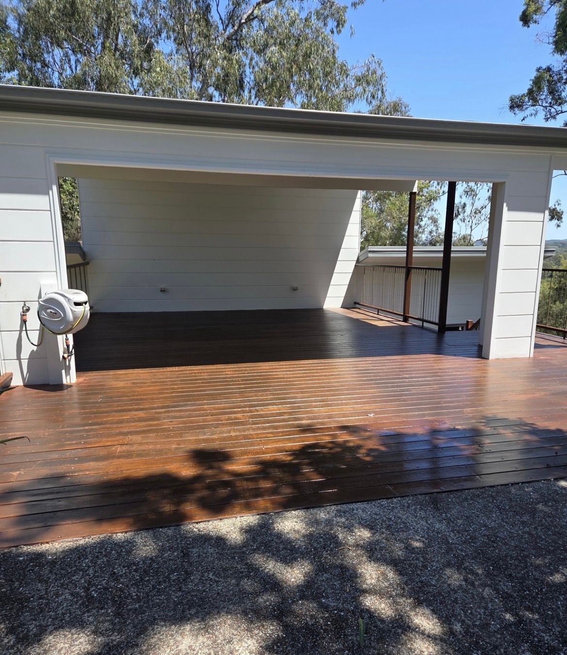 Wooden patio with brown, textured surface under a white-walled carport — MVP Painting Professionals in Maroochydore, QLD