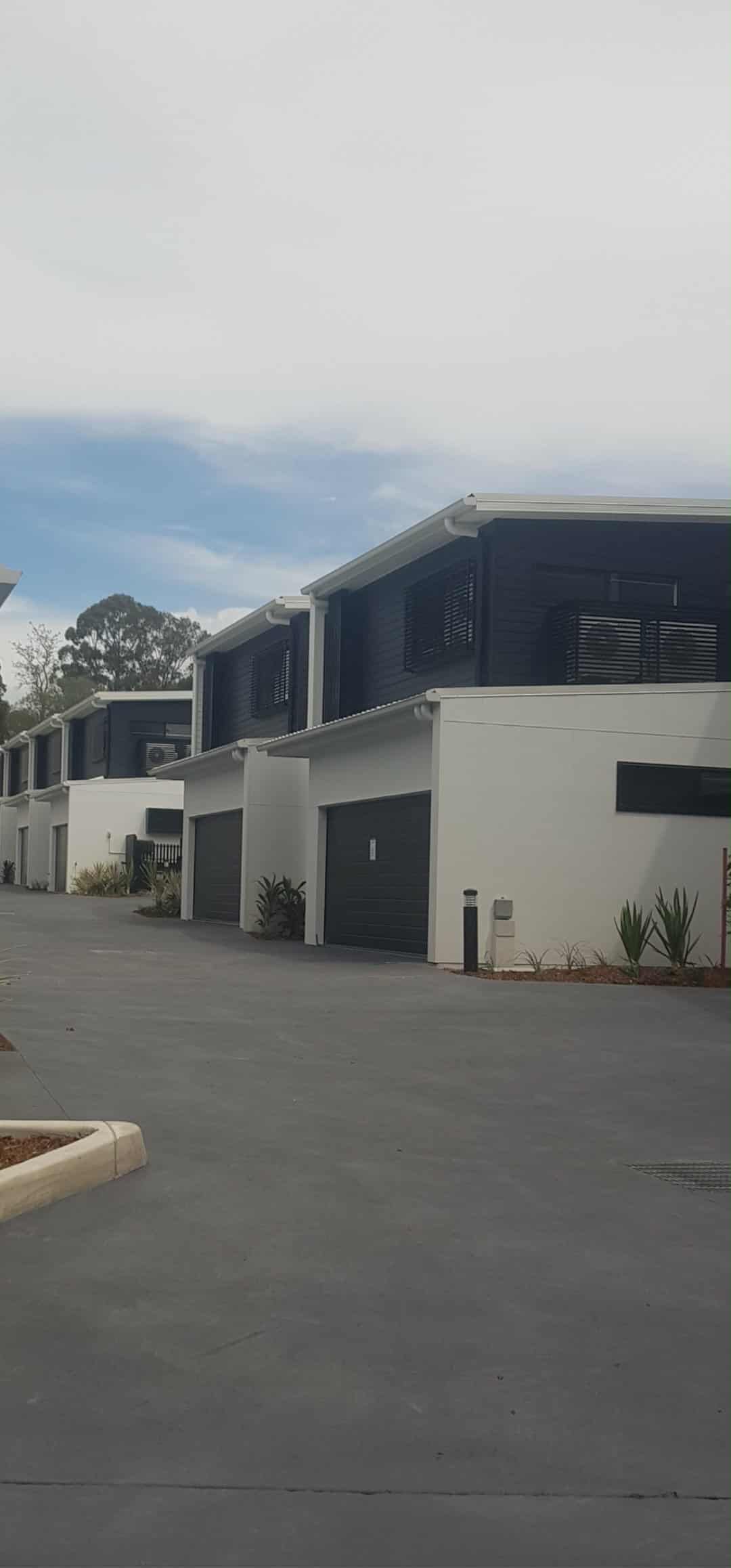 Row of modern buildings with white walls, black garage doors — MVP Painting Professionals in Nambour, QLD