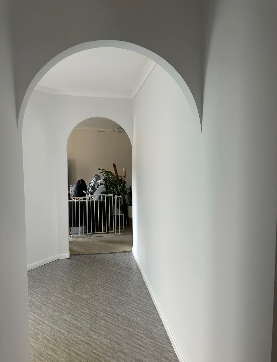 Hallway with grey flooring and white walls, arched doorway — MVP Painting Professionals in Nambour, QLD