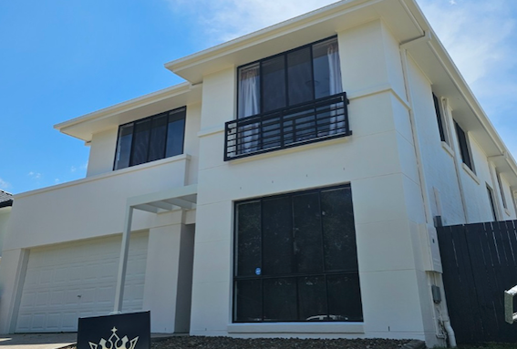 Two-story white house with black window frames, small balcony, and garage on a sunny day — MVP Painting Professionals in Sunshine Coast, QLD