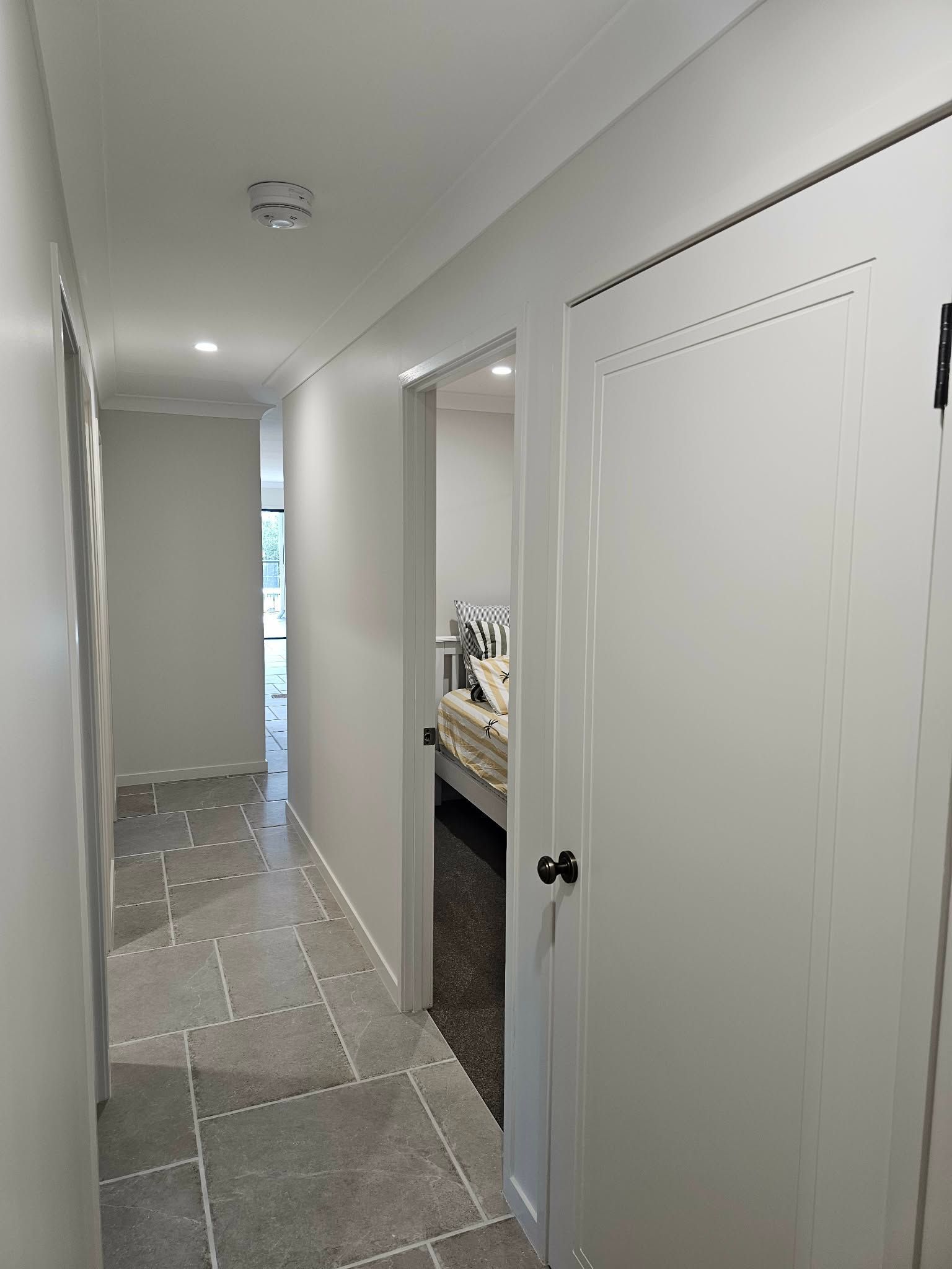 a Hallway With a Tile Floor, White Walls, Doors, and a Glimpse of a Bedroom — MVP Painting Professionals in Kawana, QLD
