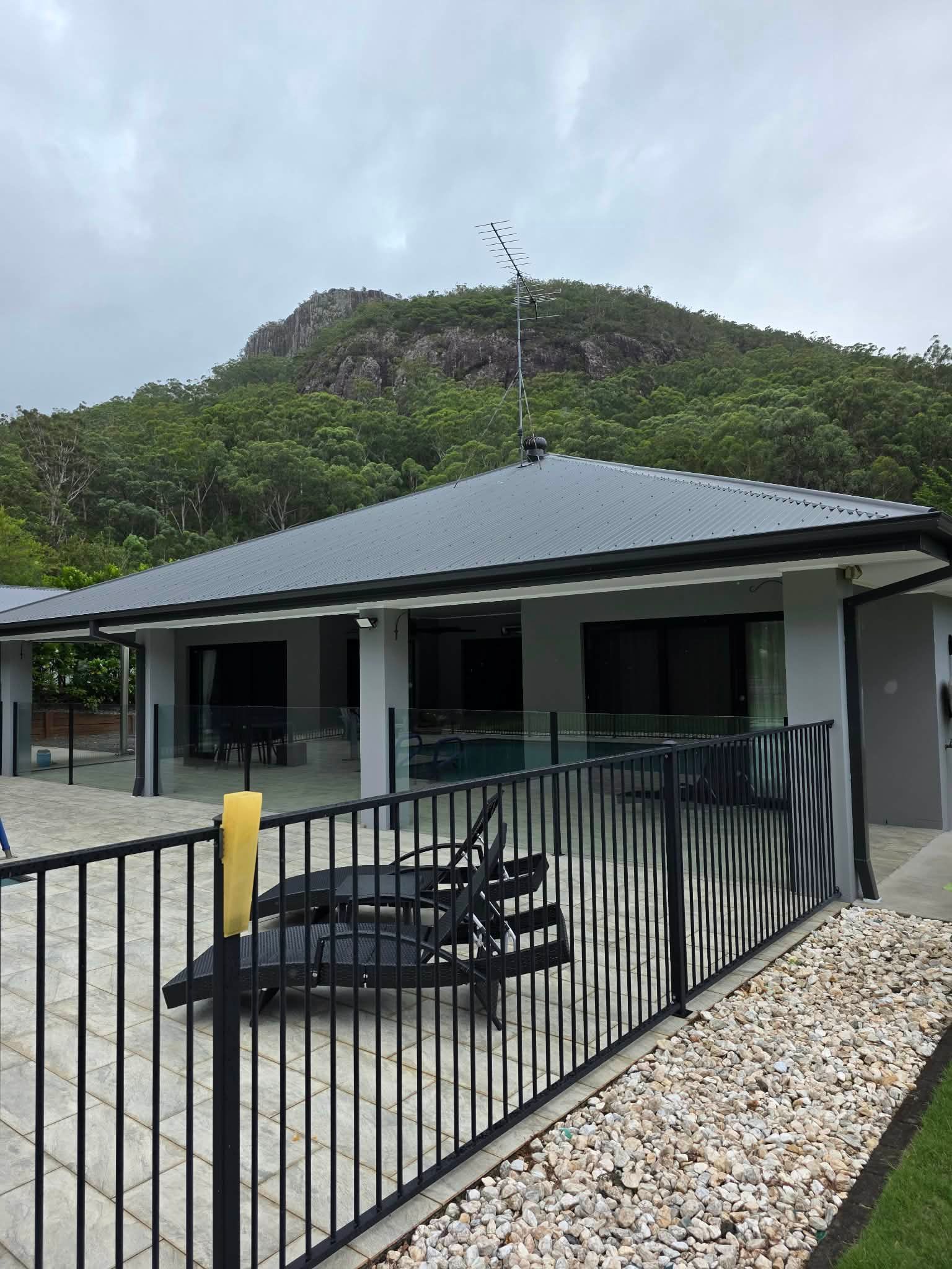 A Black Fenced Pool Deck With Lounge Chairs — MVP Painting Professionals in Sunshine Coast, QLD