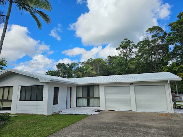White house with a garage, green grass, driveway, and blue sky with clouds— MVP Painting Professionals in Noosa, QLD