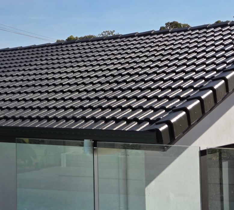 Dark gray tiled roof on a modern building, with glass railing visible below, under a blue sky— MVP Painting Professionals in Sunshine Coast, QLD