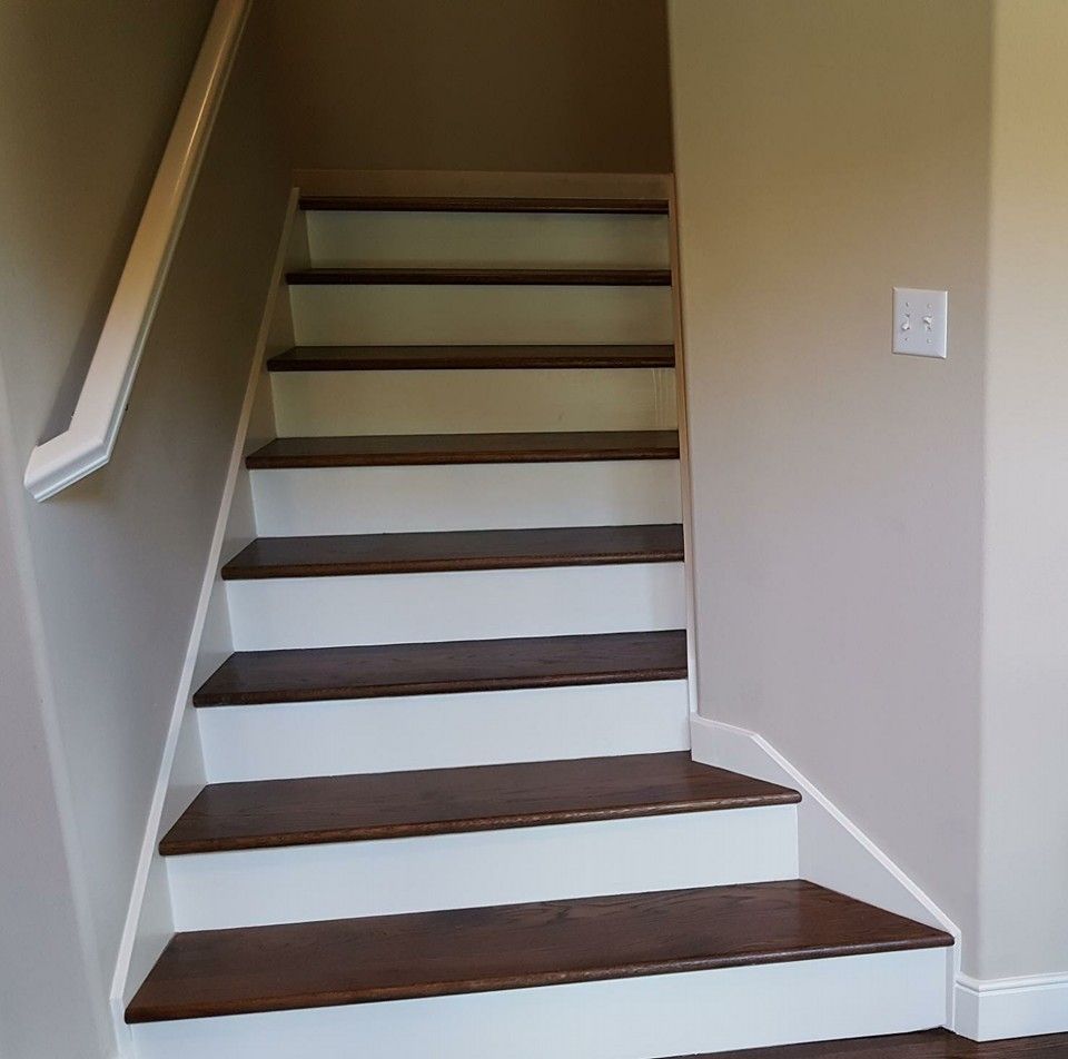 Staircase with wooden steps and white risers, ascending between tan walls, white handrail on the left.