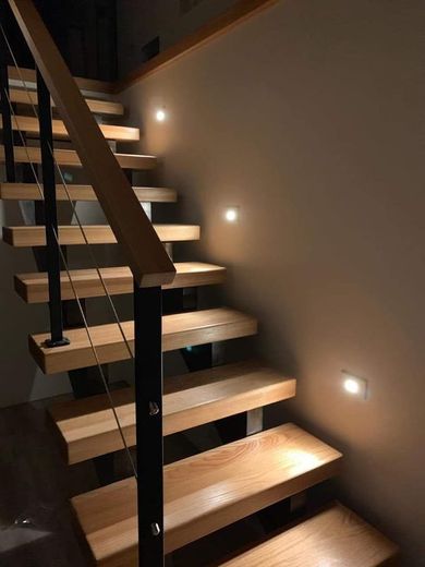 Wooden staircase with metal railing and wall-mounted lights.