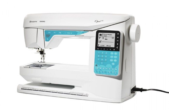 Una macchina da cucire bianca e blu è appoggiata su una superficie bianca.