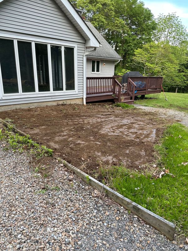 A house with a deck and a gravel driveway in front of it.