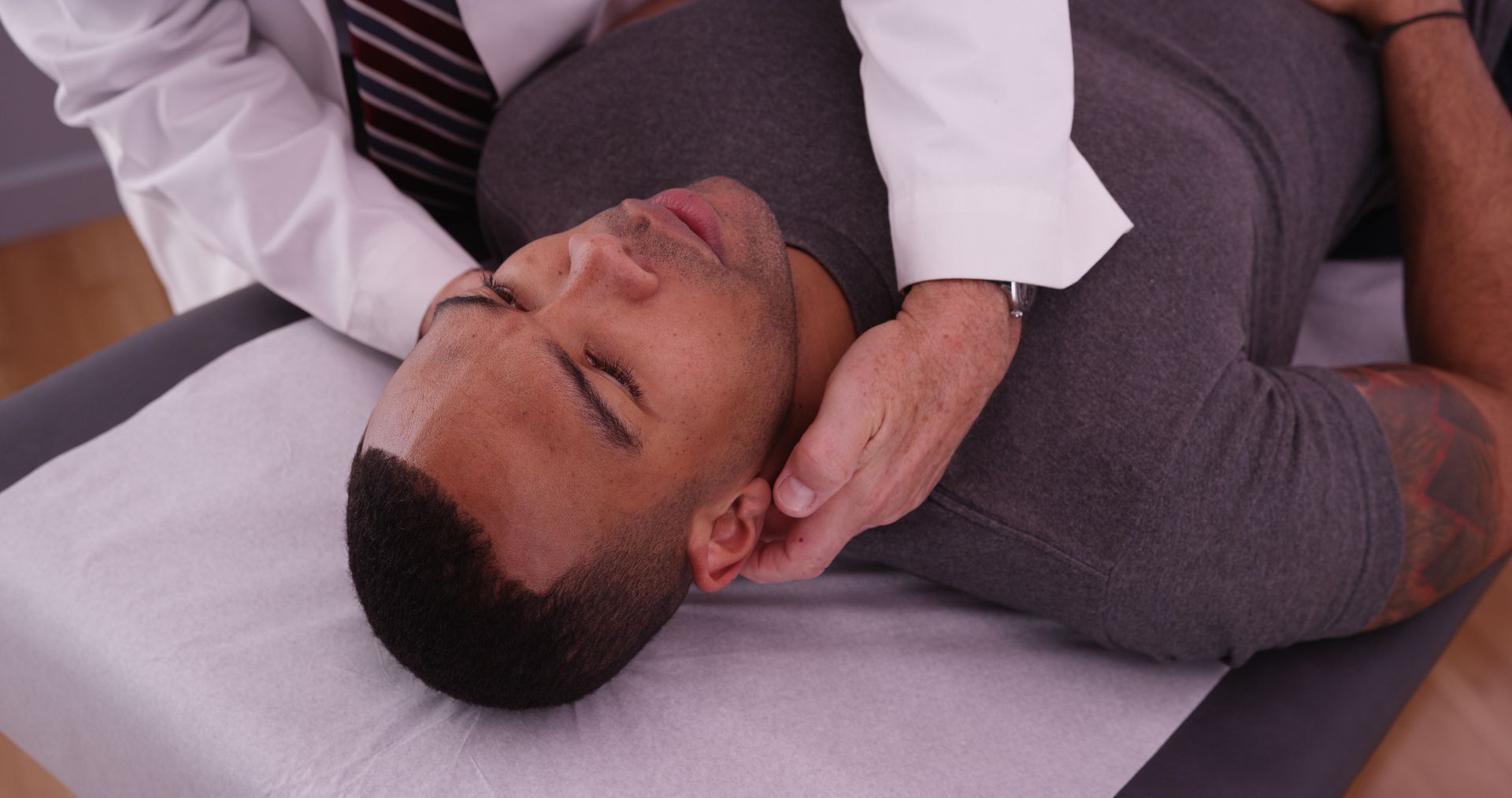 Man receiving a neck adjustment from a doctor in a medical setting.